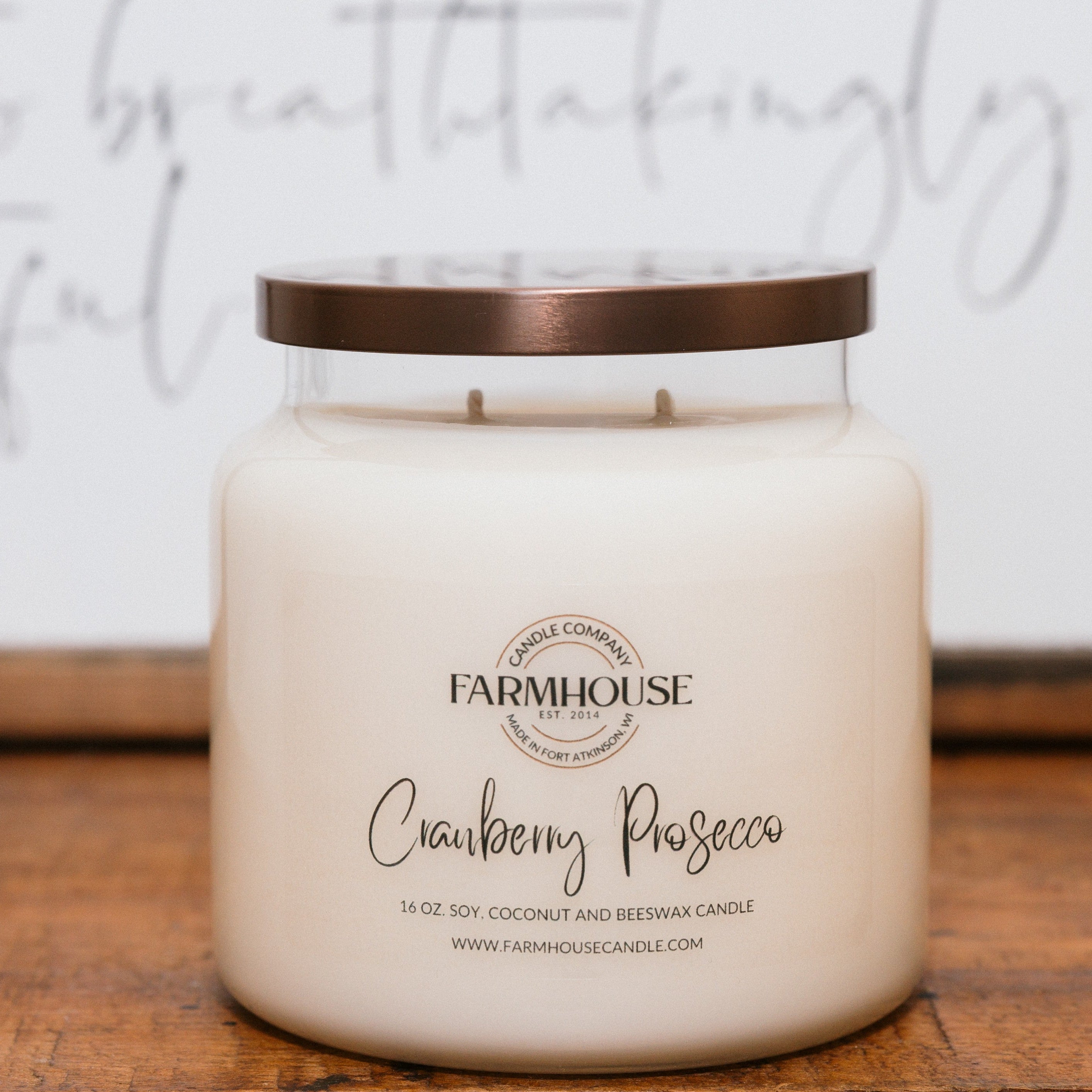 Farmhouse Candle Company cranberry prosecco candle on a wooden surface with a blurred background