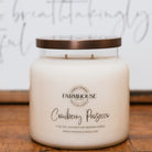 Farmhouse Candle Company cranberry prosecco candle on a wooden surface with a blurred background